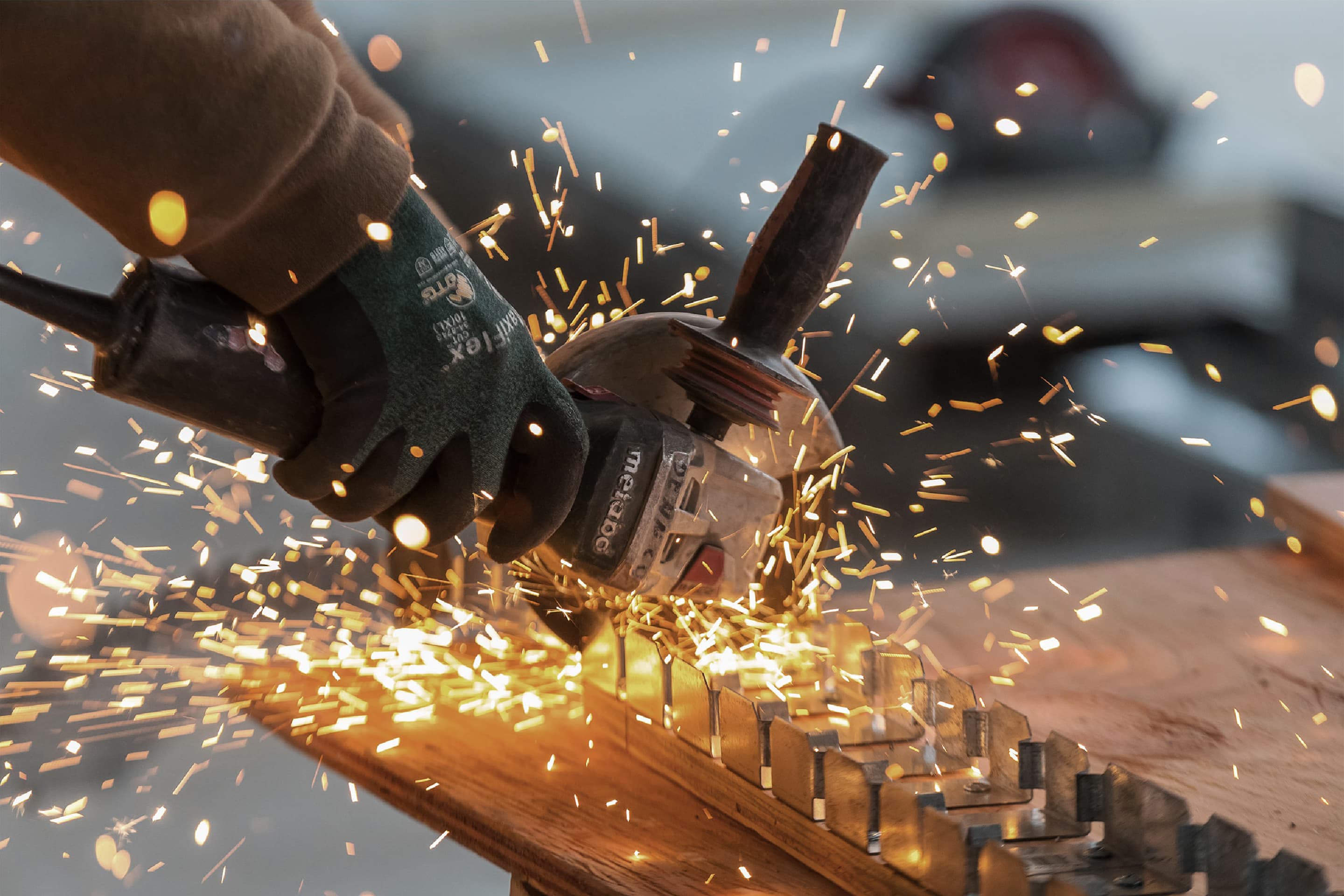 A closeup of sparks flying off from grinding a metal part with an electric grinder.