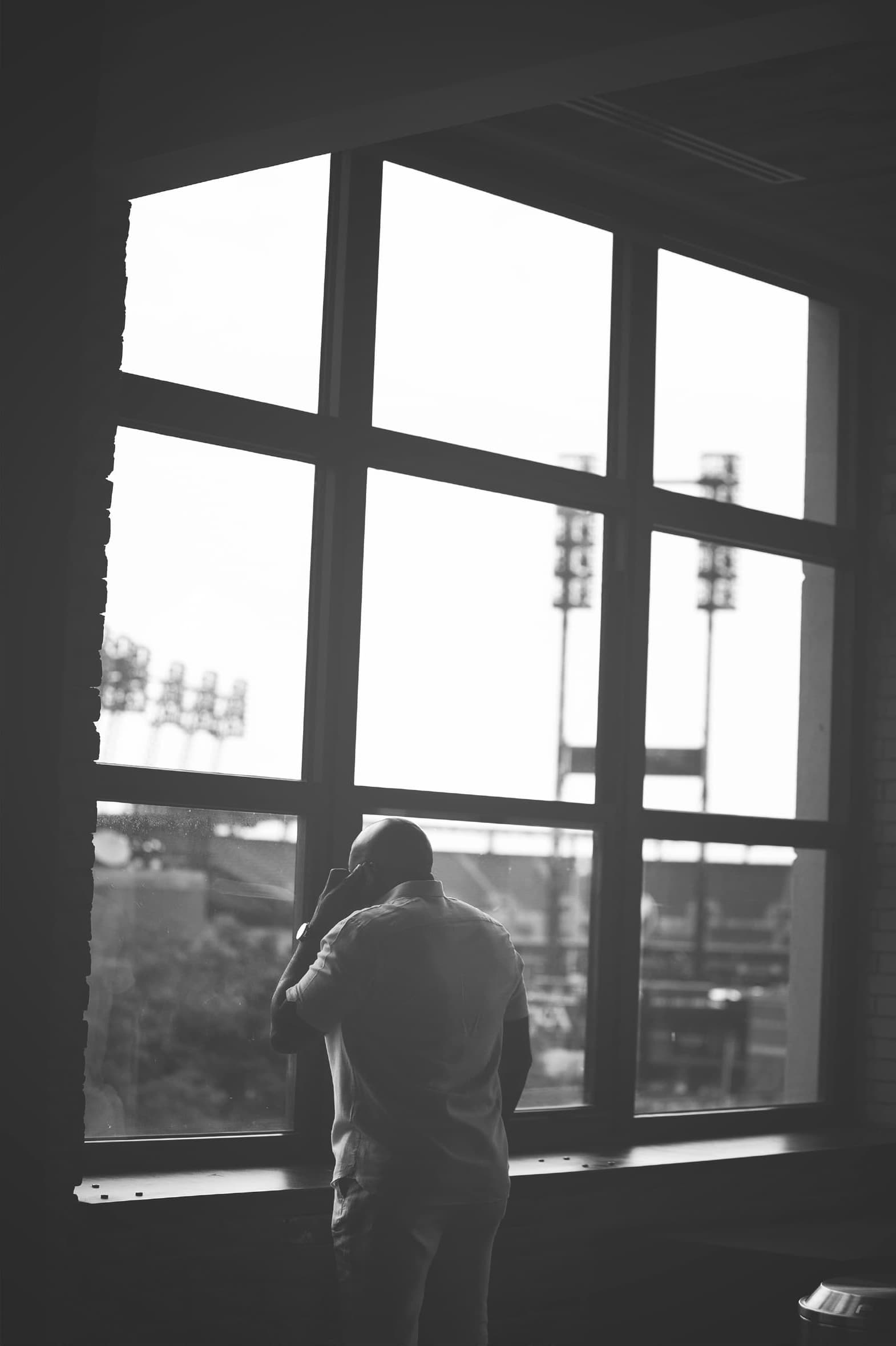 Black and white photo of Larry Brinker, Jr. over looking the Comerica Park from the office window.