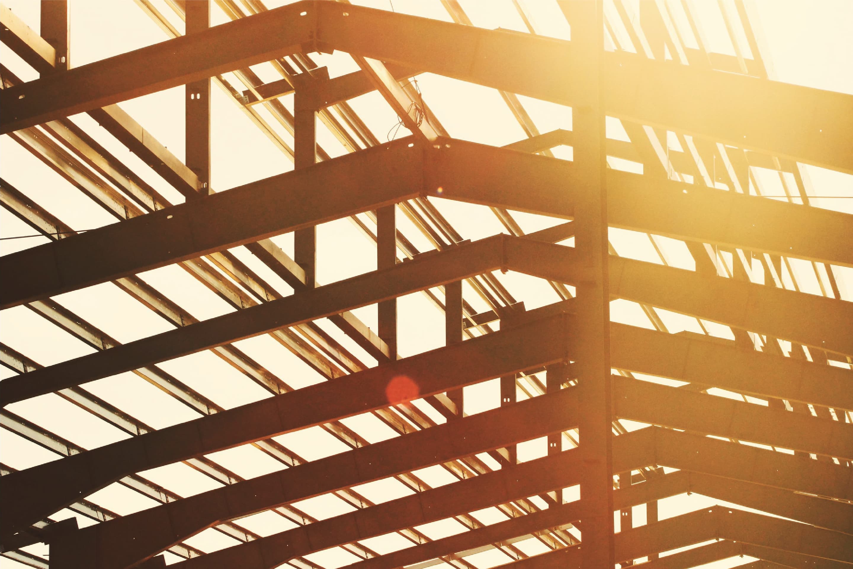 Silhouette of metal trusses against the brightly lit evening sky.