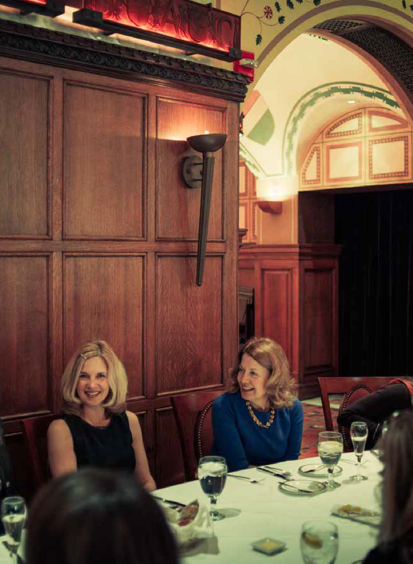 Female members similing and socializing at a dining table.