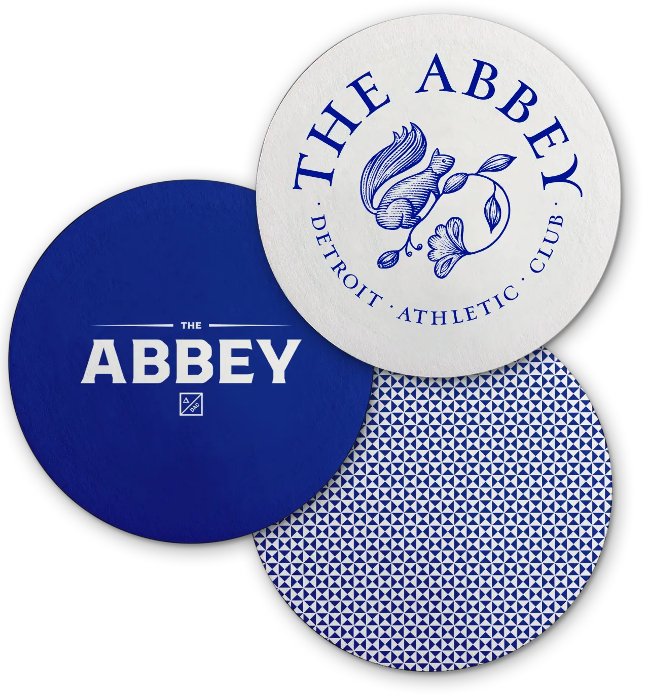 Mockup of blue and white buttons with the two Abbey logo on each and another button with the repeating blue and white triangle pattern.