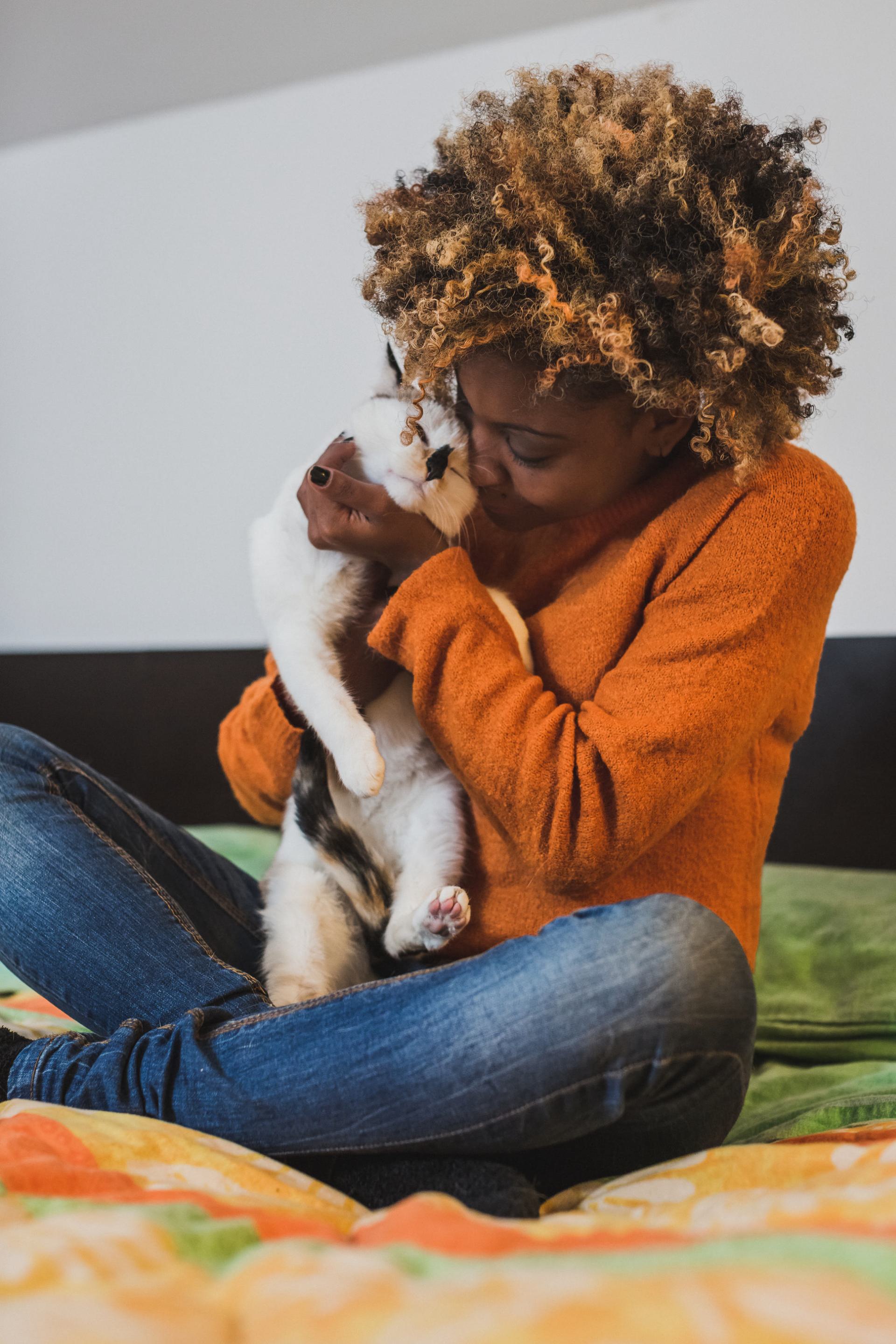 A woman hugging her cat while sitting on her bed